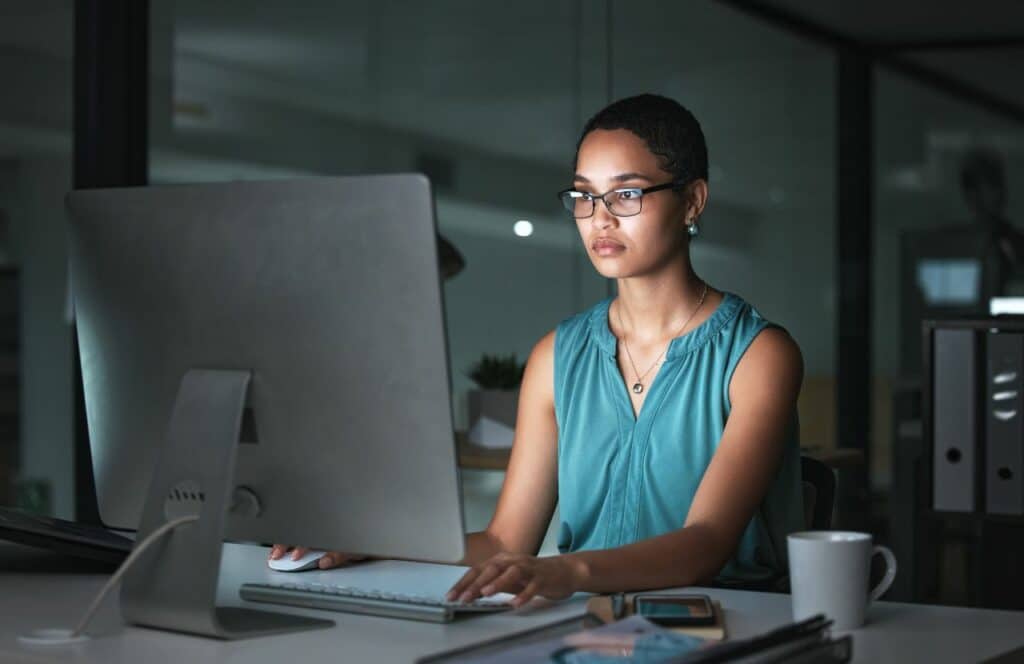 A woman sitting in a dimly lit room and allowing herself to write freely in a stream of consciousness. Keep reading for tips on how to write blog posts faster.