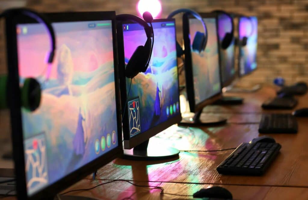 Several desktop computers with bright purple and pinks screens on a long table. Learn more about conversion rate optimization for your blog.