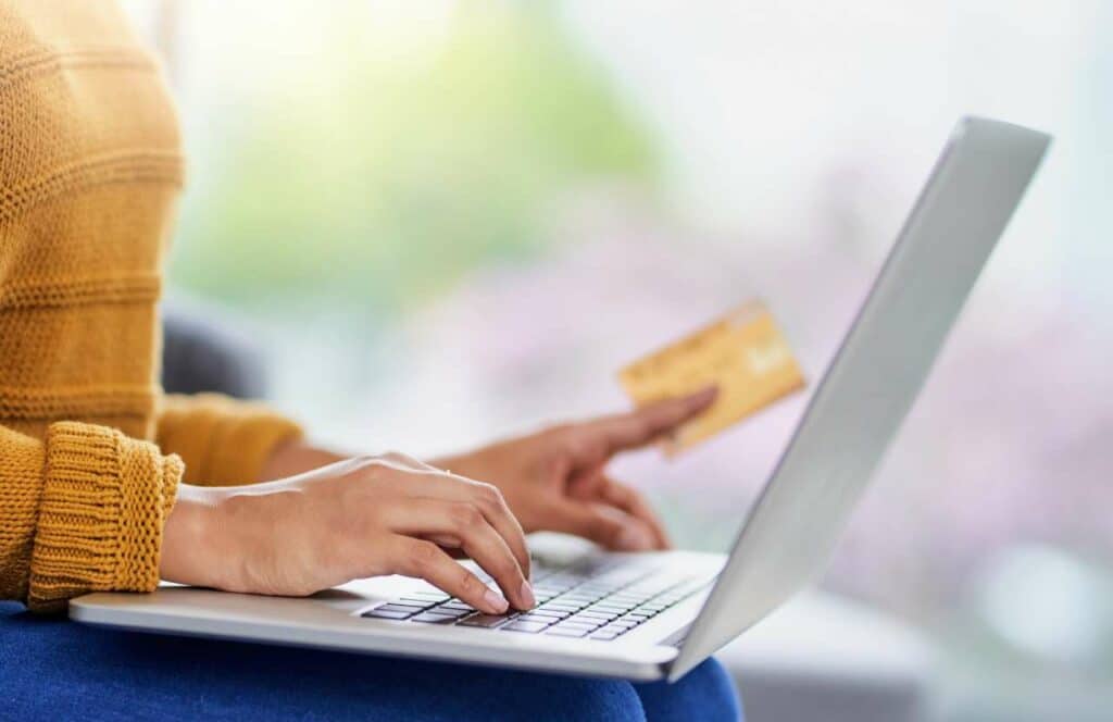 A person making a purchase on their laptop with a discount code in hand as a result of reading blog content. Learn more about how content is king and can help your business or brand.