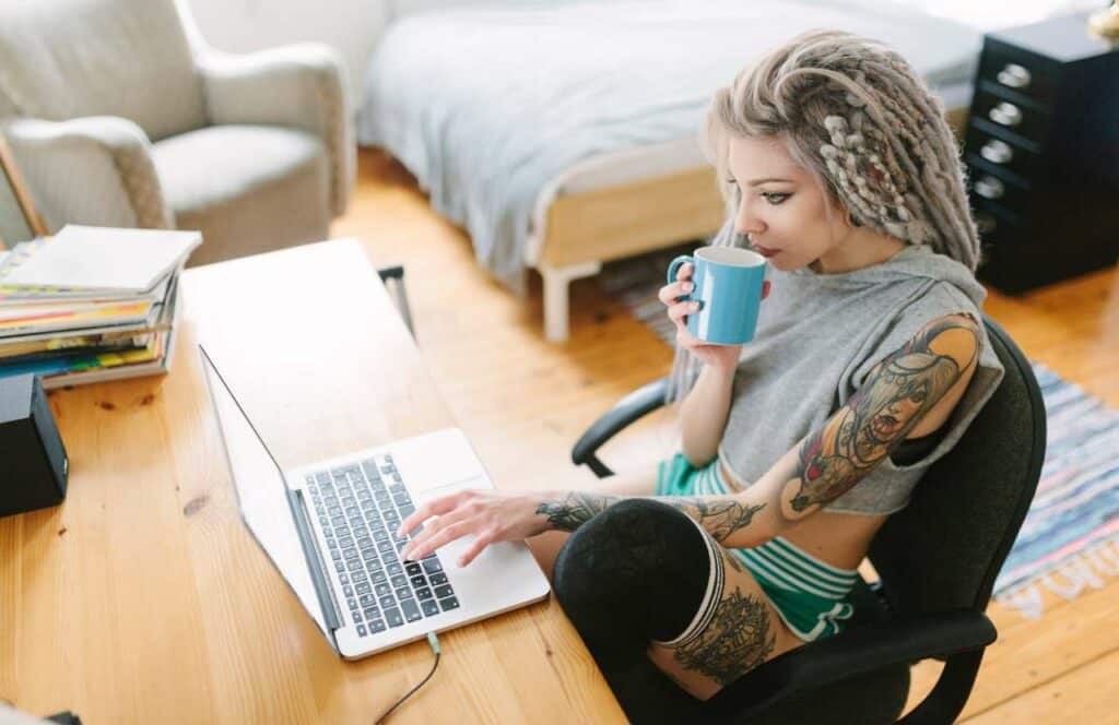 A young woman sitting with a cup of tea and her laptop at her desk while working on her blog brand awareness. If you want to learn how to build brand awareness for your blog, then keep reading.