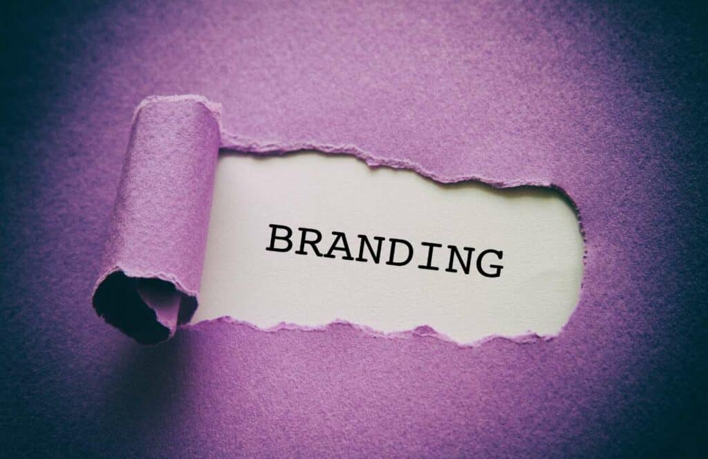 The word "BRANDING" revealed behind a torn piece of purple construction paper. If you want to learn how to build brand awareness for your blog, then keep reading.