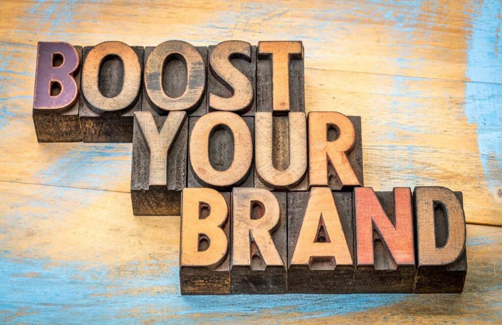 The words "boost your brand" spelled out with wooden blocks on a wooden table surface. If you want to learn how to build brand awareness for your blog, then keep reading.