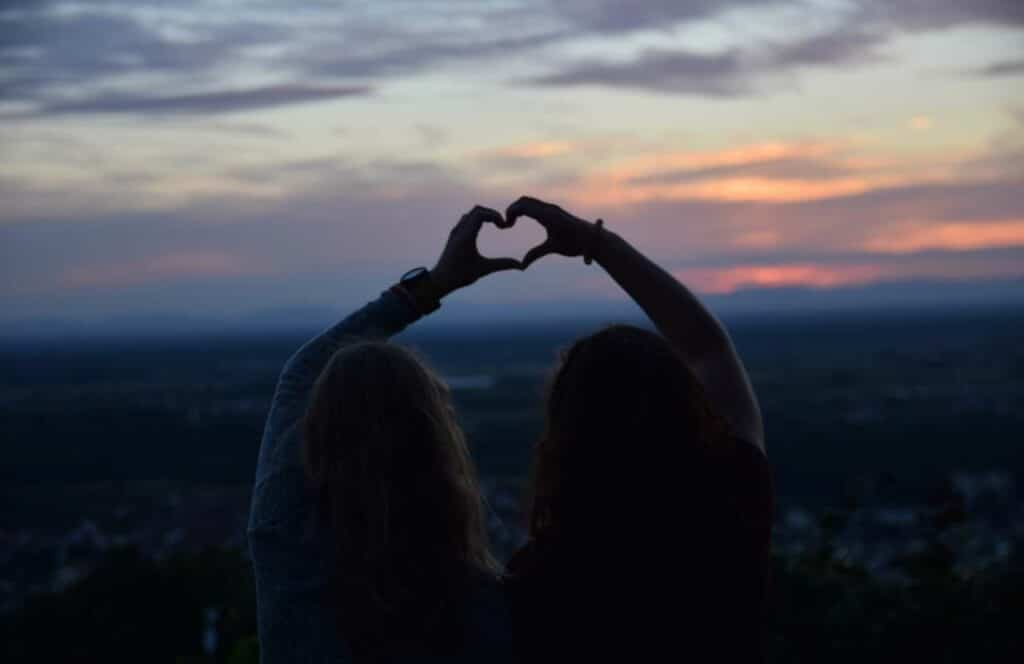 Two people holding up their hands to the evening sky, while forming a heart as their hands touch. If you want to learn how to build brand awareness for your blog, then keep reading.