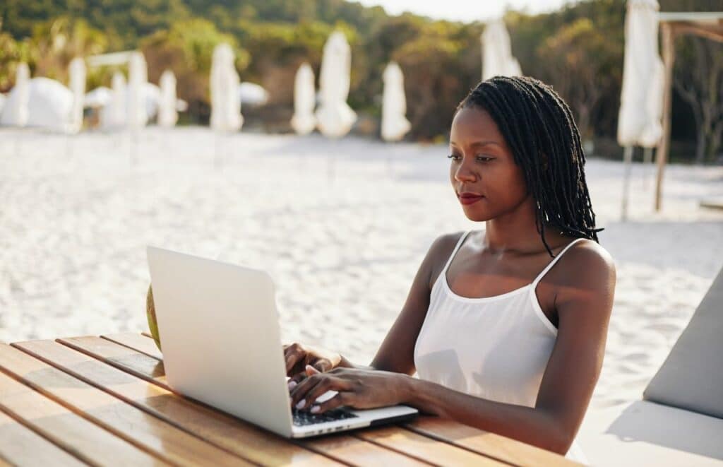 Black Lady blogger writing on computer on the beach