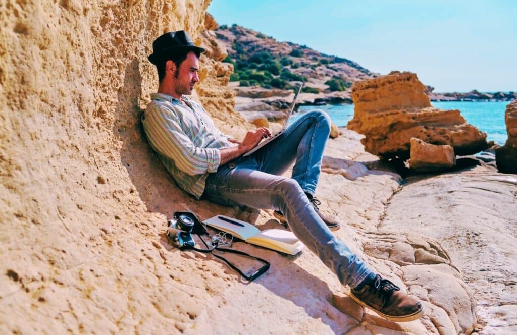 Male freelance writer working near the sea on a blog post. Keep reading to know How Much to Charge for a Blog Post