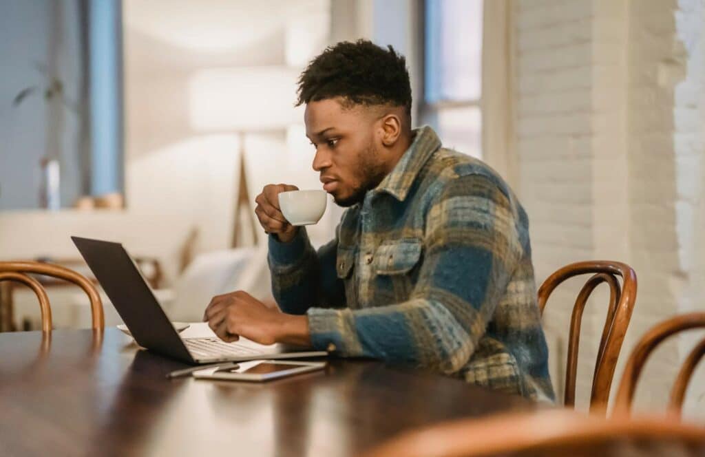 A black man sitting at his desk attending a virtual summit for his favorite blogger. Keep reading to learn how to monetize your blog from day one.