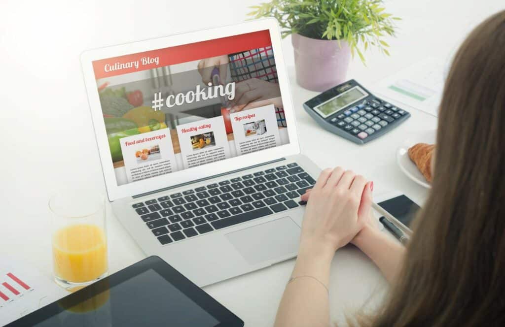 A woman sitting at her desk and designing her blog to include sidebars and widgets. Keep reading to learn how to monetize your blog from day one.