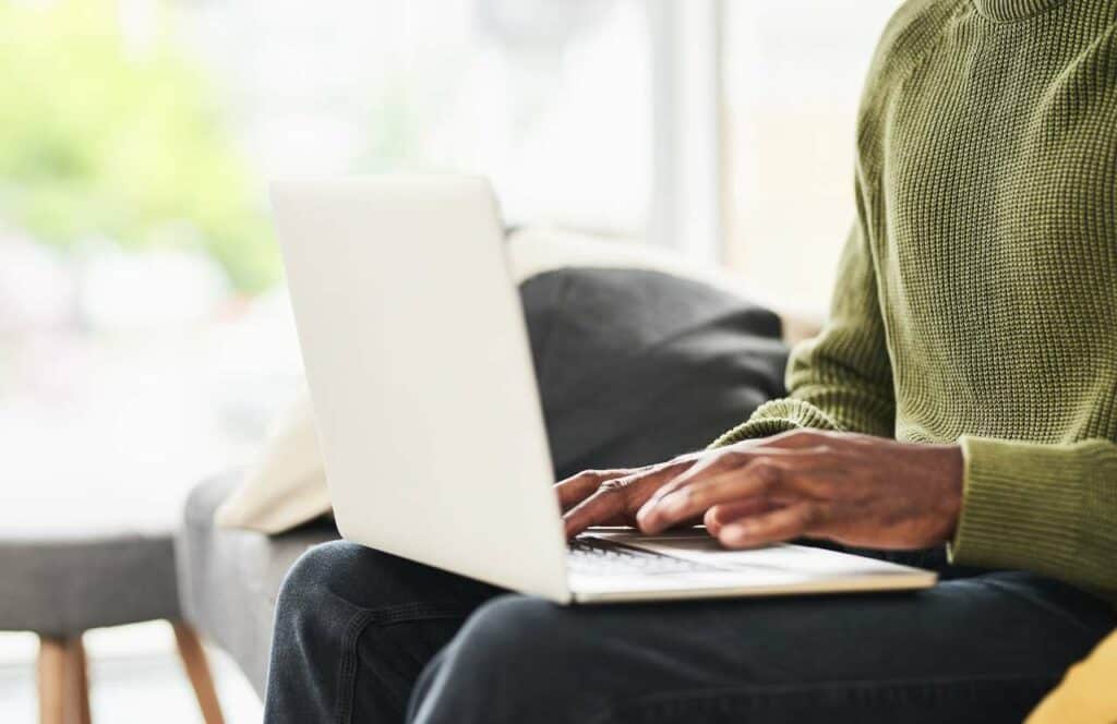 A black man sitting while sitting on the couch while creating valuable content for his blog. If you have ever asked "What's the point of blogging?" click here to read more.