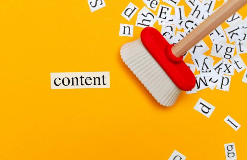 A cut out of the word "content" and several alphabet letters on a yellow background being swept up by a broom. Keep reading to learn more about the best strategies to curate content for your blog.
