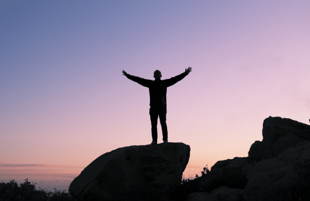 A man standing on top of a hill symbolizing freedom since leaving his job to blog full-time. Keep reading to learn the answer to the question, "Is Blogging Still Relevant?"