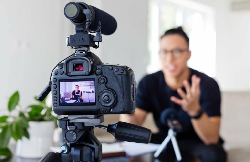 A man with a glasses sitting in front of a camera recording content for his blog audience and YouTube channel. If you have ever asked "What's the point of blogging?" click here to read more