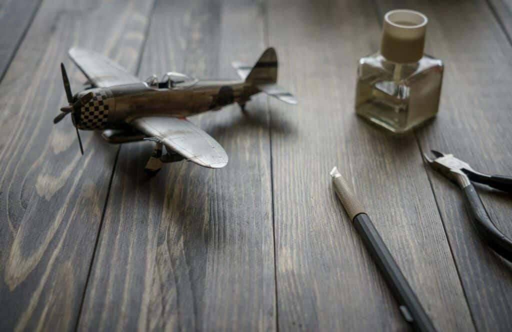 A model airplane sitting on a wooden table with supplies that will be shared on a hobby blog. If you have ever asked "What's the point of blogging?" click here to read more.