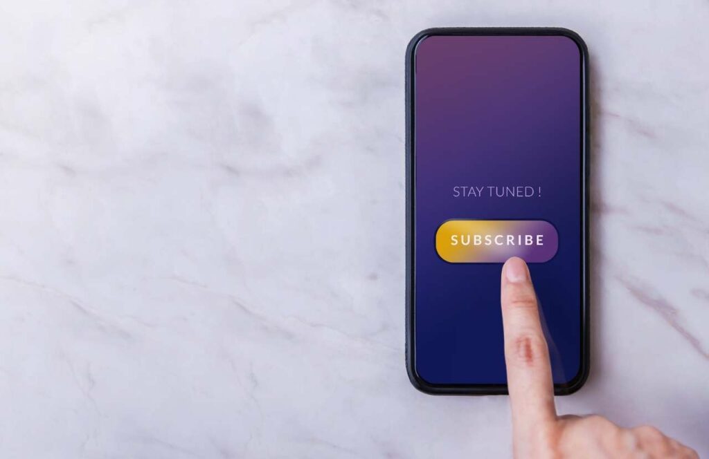 A person tapping on a subscribe button on their phone. Keep reading to learn more about how you can increase website conversions.