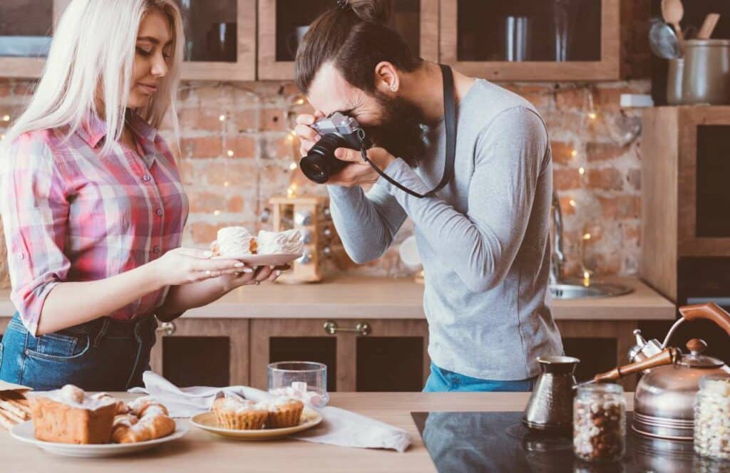 A woman holding a desert plate with fresh baked goods while a man takes upclose photos for a food blog. If you have ever asked "What's the point of blogging?" click here to read more.