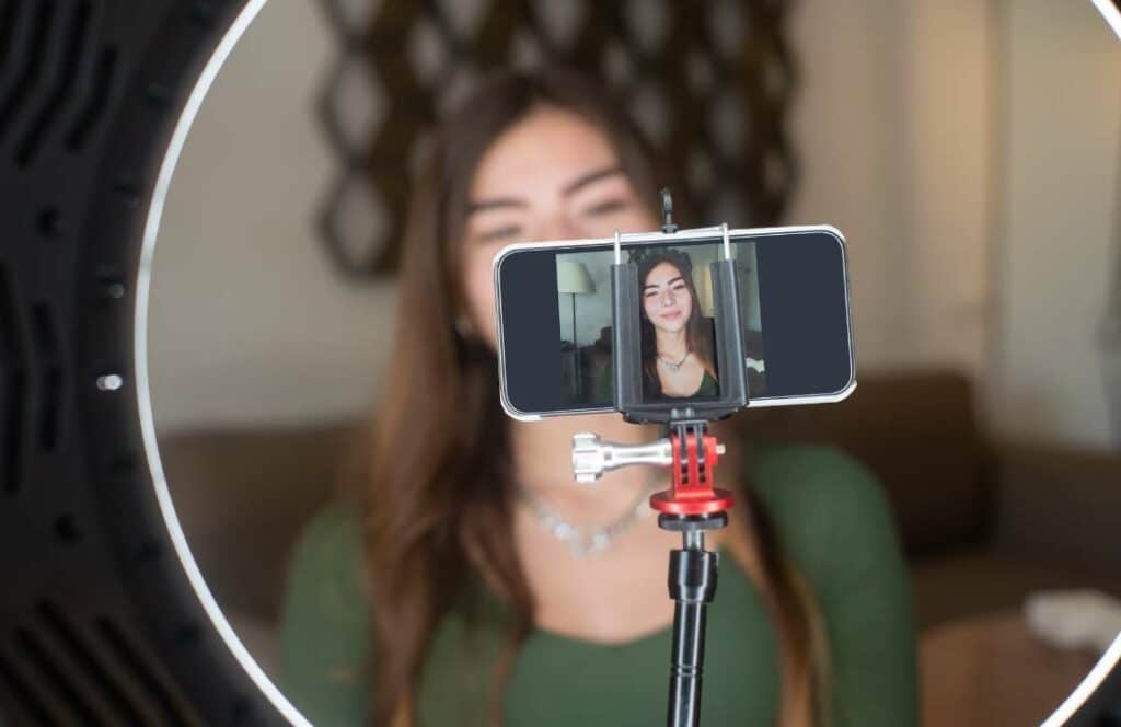 A woman recording videos with her phone and ring light for social media and her blog. If you've ever wondered "What's the point of blogging?" click here to read more.