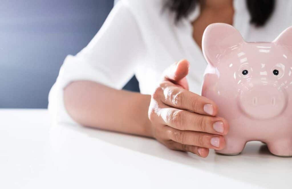 A woman touching a piggy bank in hopes that she will make a full-time income blogging someday. If you ever wondered "What's the point of blogging?" click here to read more.