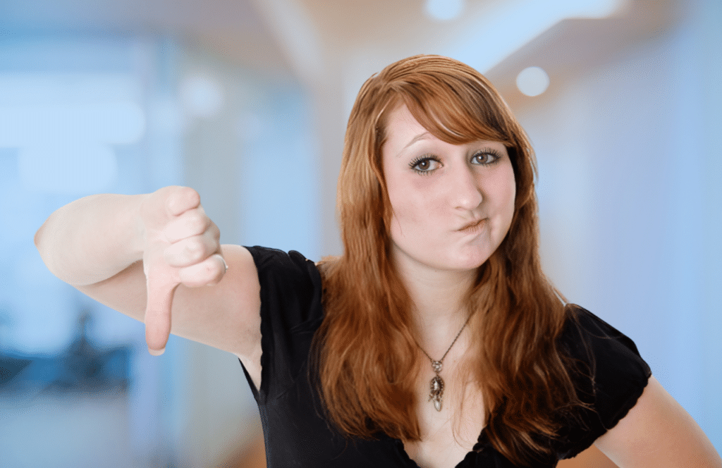 A woman with red hair standing in an office with her thumb down signifying that you should not use outdated blogging techniques. Keep reading to learn the answer to the question, "Is Blogging Still Relevant?"