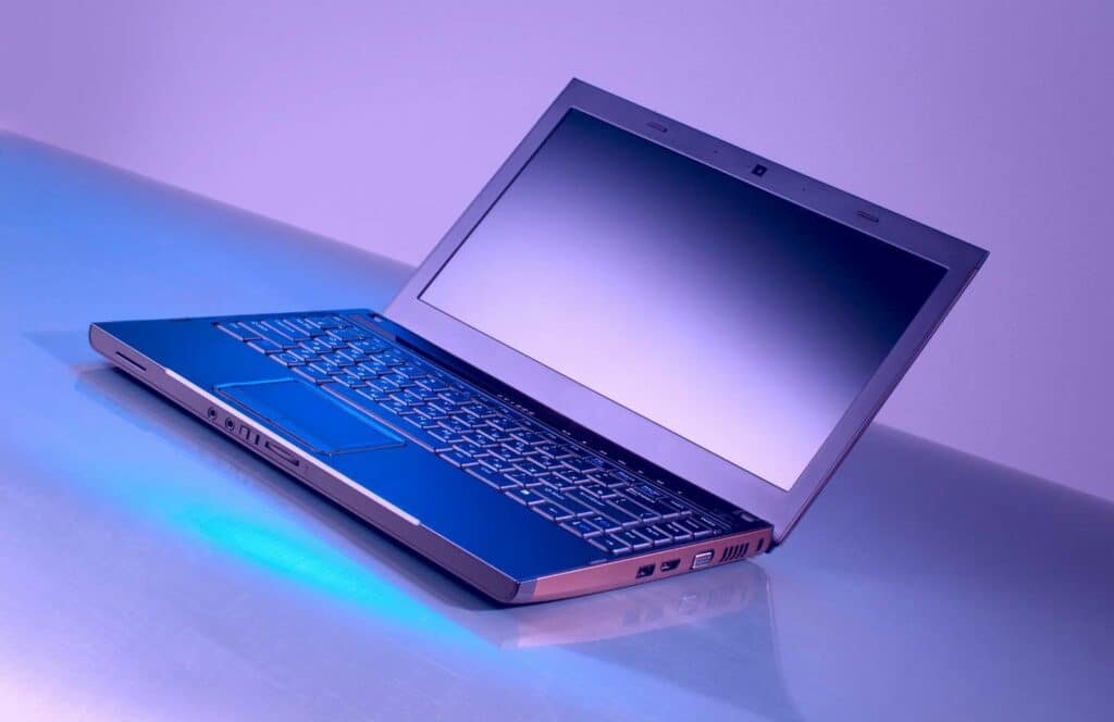 A laptop sitting open on a desk with purple background and blue lighting. Learn more about internal linking best practices by reading this blog post.