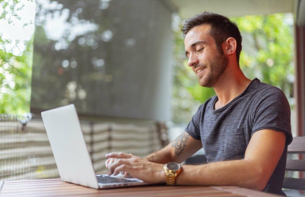 A man sitting outside on a patio while working on his blog linking strategy. Learn more about internal linking best practices by reading this blog post.