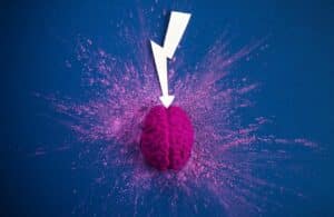 A white arrow pointing to a pink brain on a dark purple background representing knowing the difference between brand awareness and brand recognition