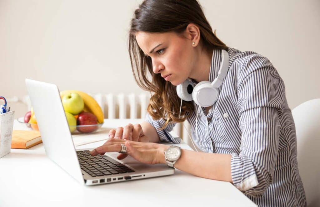 A woman sitting at a desk wearing white headphones around her neck while working on her blog linking strategy. Learn more about internal linking best practices by reading this blog post.