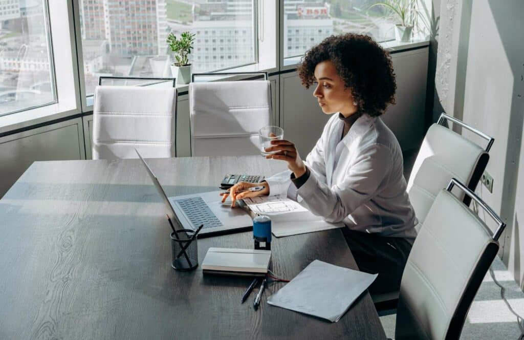 A woman with curly short hair sitting at a desk while working on her blog linking strategy. Learn more about internal linking best practices by reading this blog post.
