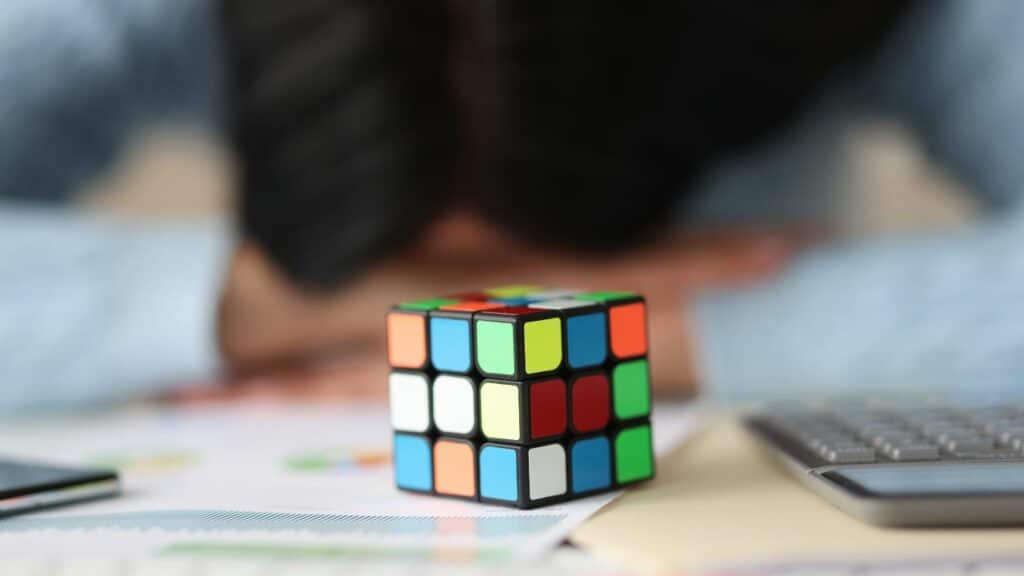A person holding a Rubik's Cube on a desk. Click here to learn more about affiliate vs partner marketing for bloggers.